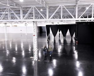 panoramica dall'alto della location pavimento nero con rifelssi di luce e soffitto con struttura tubi in bianco acciaio